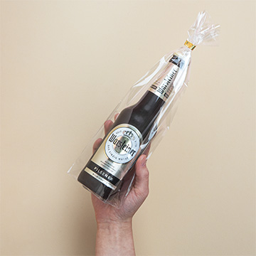 Eine Flasche Schokoladenbier in Geschenkfolie verpackt in einer Hand präsentiert