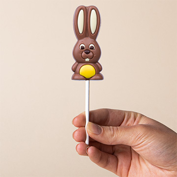 Gelber Schokoladenhase zu Ostern, in der Hand pr&auml;sentiert