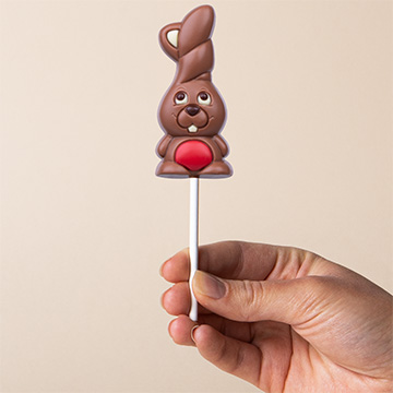 Roter Schokoladenhase zu Ostern in der Hand pr&auml;sentiert