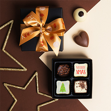 ein mit Bändern zusammengebundenes Set belgischer Schokoladenpralinen mit Weihnachtsaufdruck