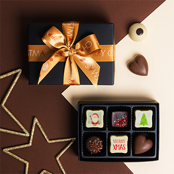 ein mit Bändern zusammengebundenes Set belgischer Schokoladenpralinen mit Weihnachtsaufdruck