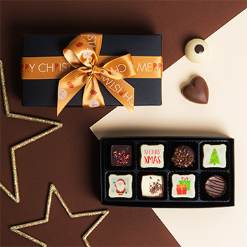 ein mit Bändern zusammengebundenes Set belgischer Schokoladenpralinen mit Weihnachtsaufdruck
