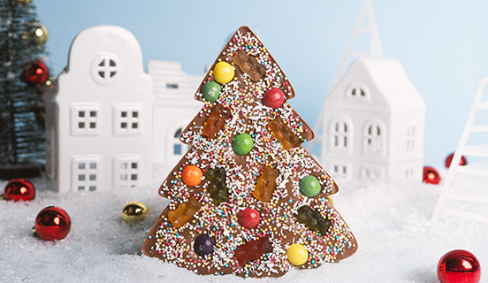 Zusätze in einen XL-Weihnachtsbaum aus Milchschokolade getaucht