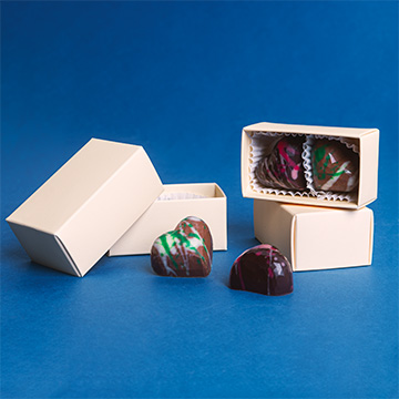 ein Set aus zwei herzförmigen Pralinen mit Pistazien- und Himbeerfüllung