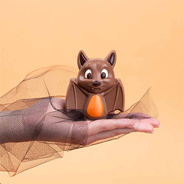 Halloween-Fledermaus aus belgischer Schokolade auf einer Hand präsentiert