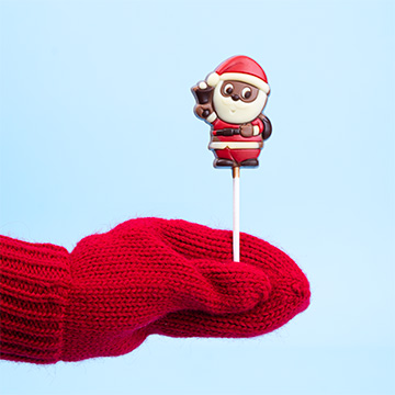 ein Schokoladen-Lutscher in Form eines Weihnachtsmanns, der in einer Hand präsentiert wird