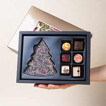 Dekorative Verpackung von Weihnachten ChocoPostcard Midi Gold in den Händen präsentiert