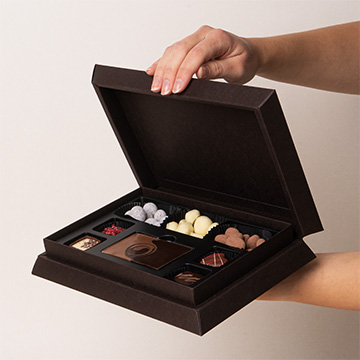 ein Set Pralinen aus belgischer Schokolade in den Händen präsentiert