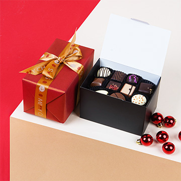 Ballotin Supreme gefüllt mit belgischen Schokoladenpralinen in einem weihnachtlichen Arrangement