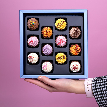 In der Hand gehaltene Pralinen in Cupcake-Form