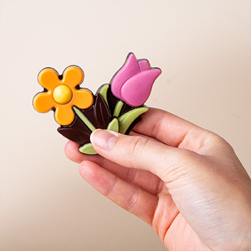 Schokoladen-Gänseblümchen und -Tulpen in den Händen