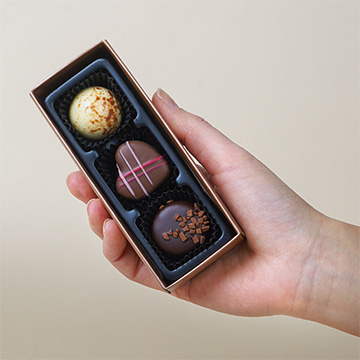 3 Pralinen aus belgischer Schokolade, präsentiert in den Handflächen