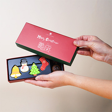 Set von Schokoladenfiguren mit Pralinen in einem weihnachtlichen Arrangement in der Hand präsentiert